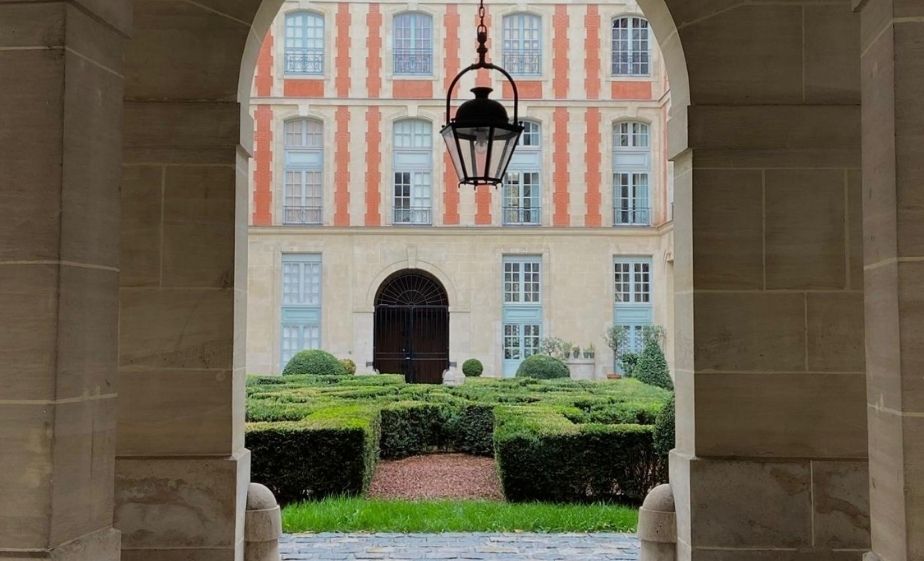Formal garden and historic building framed by a stone arch